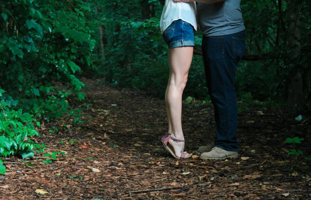 Love Spells A loving couple embracing on a secluded forest pathway surrounded by lush greenery.