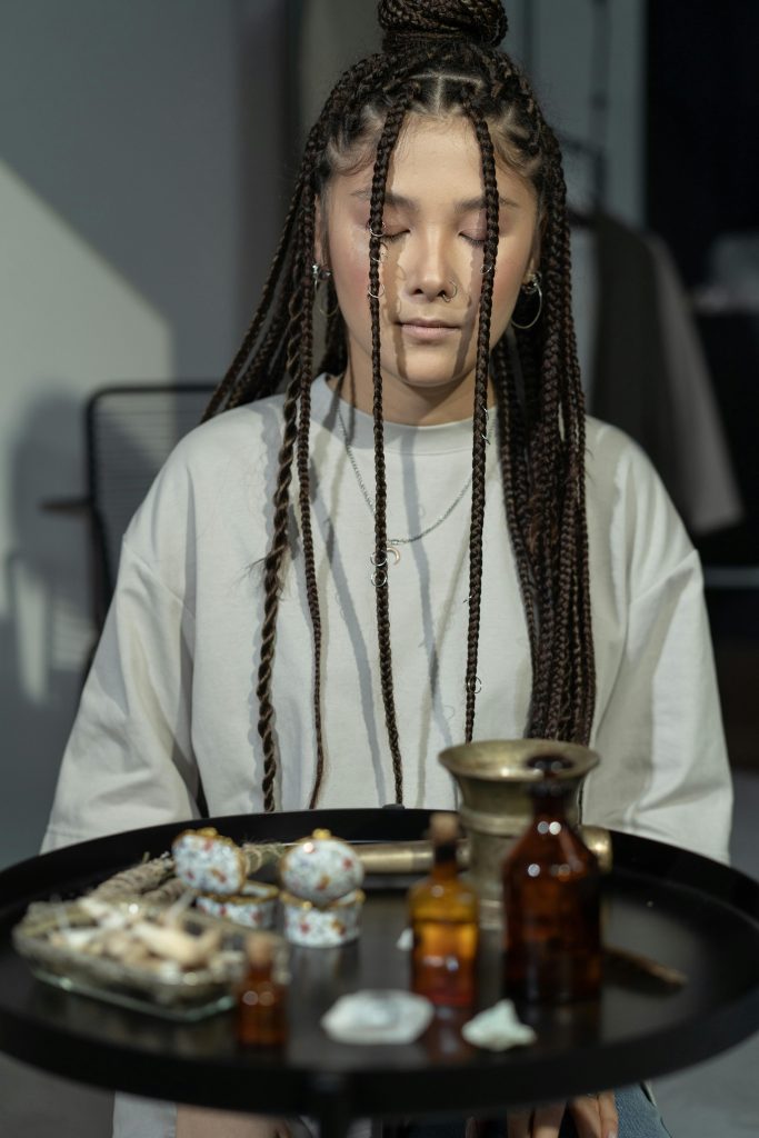 Protection Spells Young woman with braids in a mystical ritual setting, eyes closed, indoors.