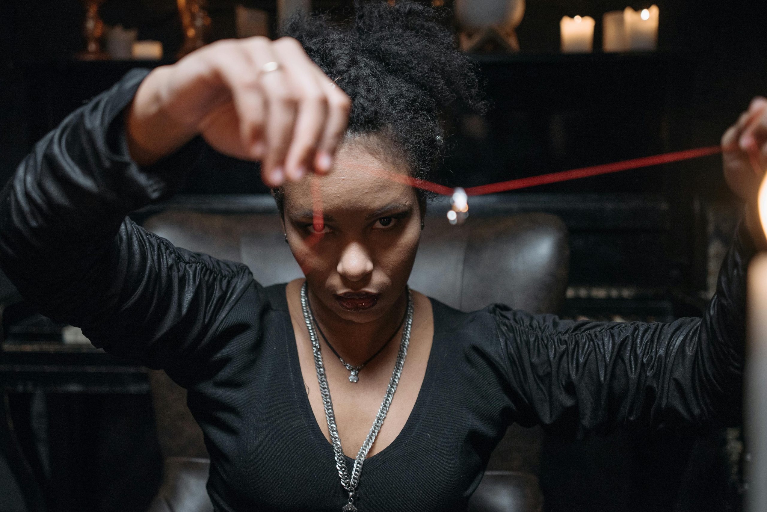 Services A young woman in a mysterious setting, holding a pendant with intense gaze and dim candlelight.