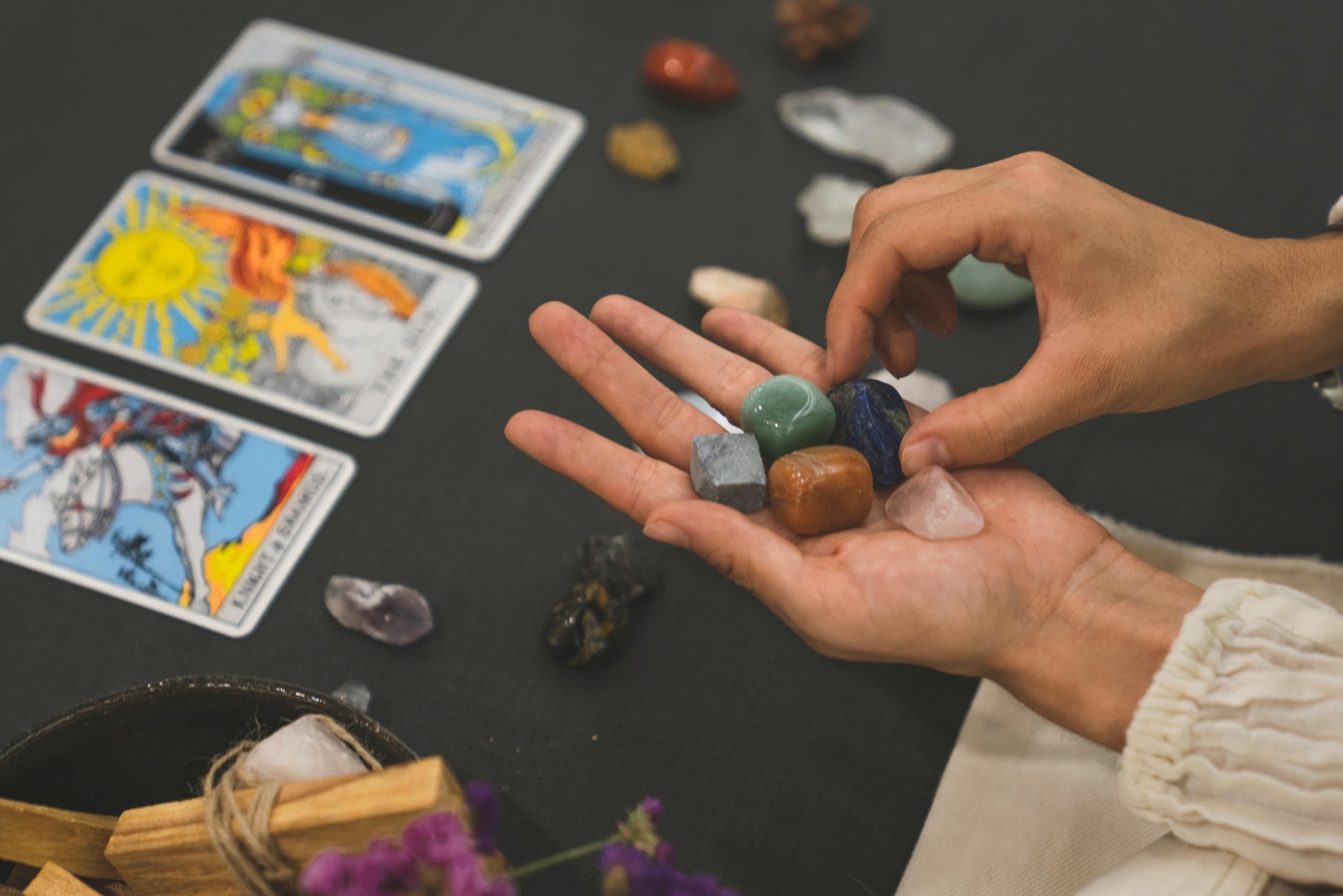 Home Person holding healing crystals with tarot cards in the background, symbolizing spirituality.